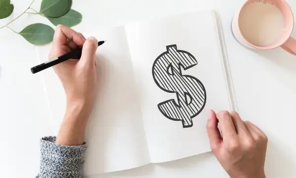 Writing in a white pad with a dollar sign